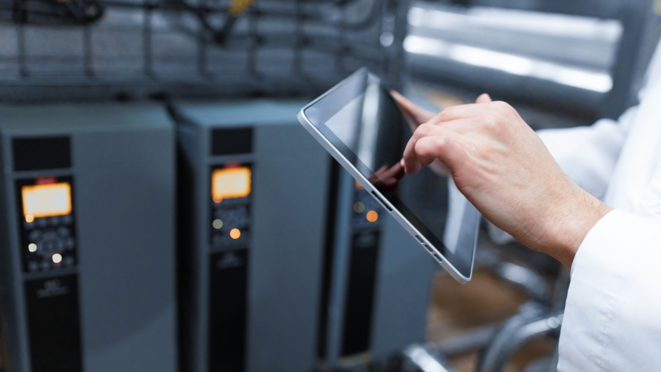 technologist with grey tablet in his hands make a set up of the production line while standing at the department of dairy factory